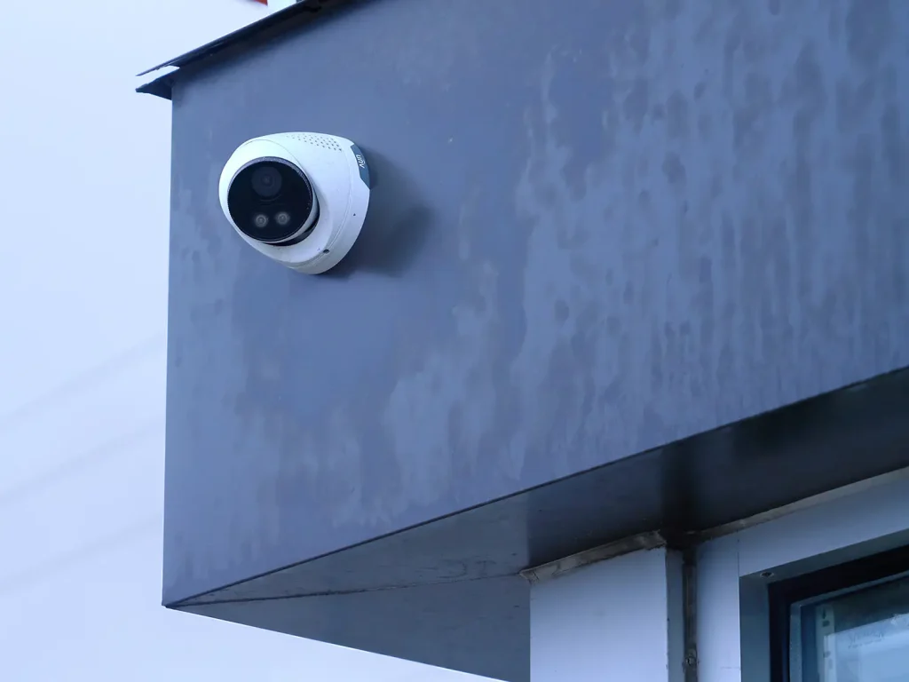 A Uniview security camera mounted to the metal roof of a building, taken during a cloudy winter day.