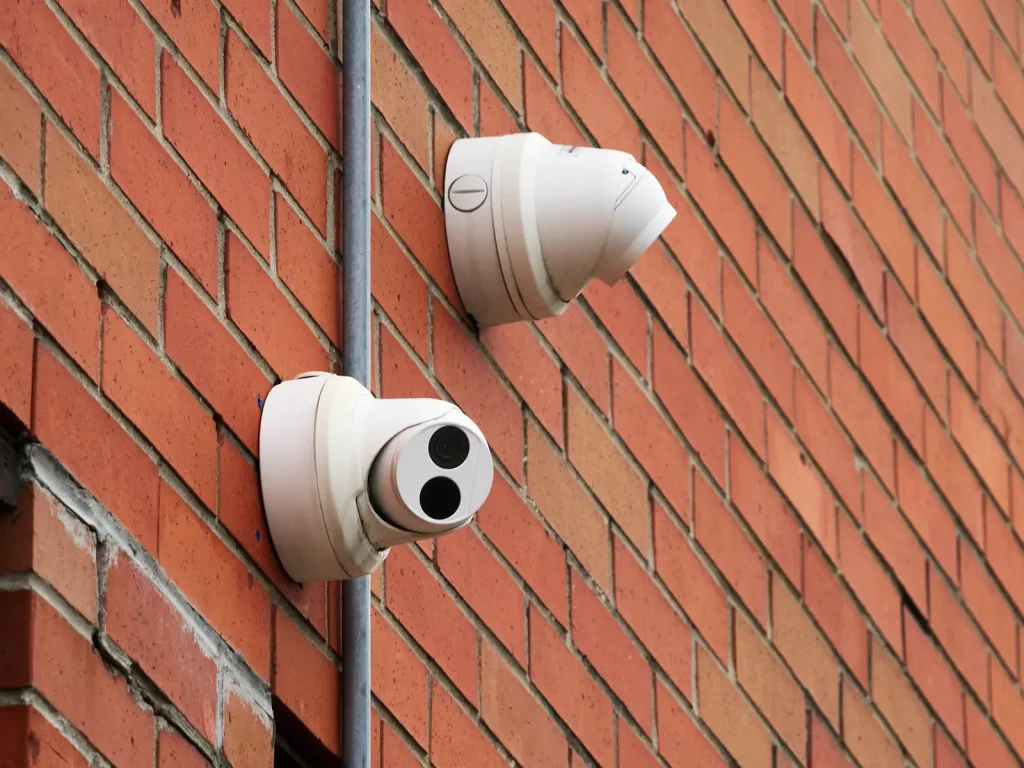 Two uniview 4MP security cameras mounted on a red brick wall with a metal conduit running between them.