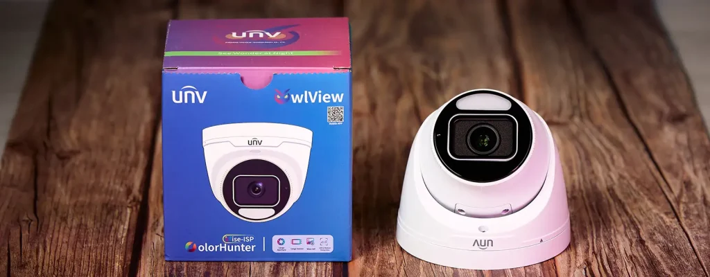 A security camera on a wooden table along with the box beside it that says OwlView ColorHunter with Wise-ISP