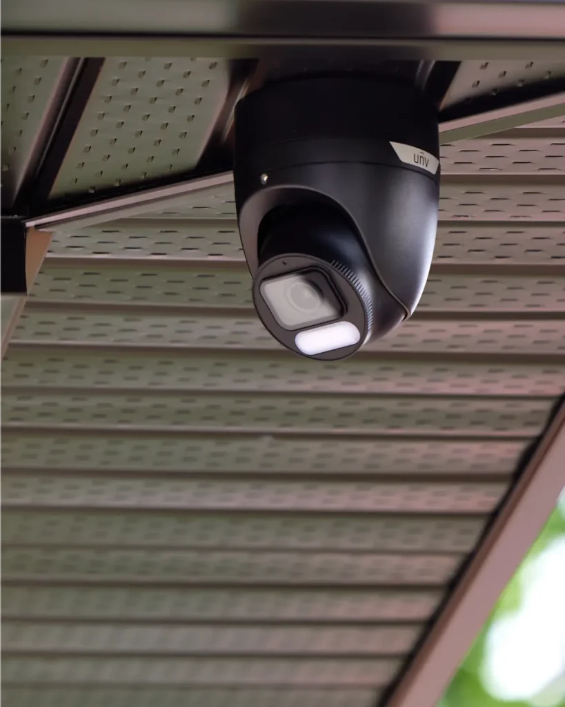 A black Uniview security camera installed into the soffit of a home