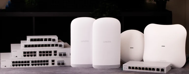 A collection of networking equipment from Lysora Networks on a table, including managed switches, wireless bridges, and access points.
